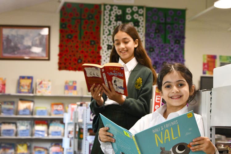 Two students sitting reading library books.