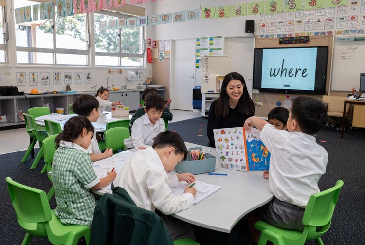 Student sitting at a table with their teacher doing a handwriting lesson