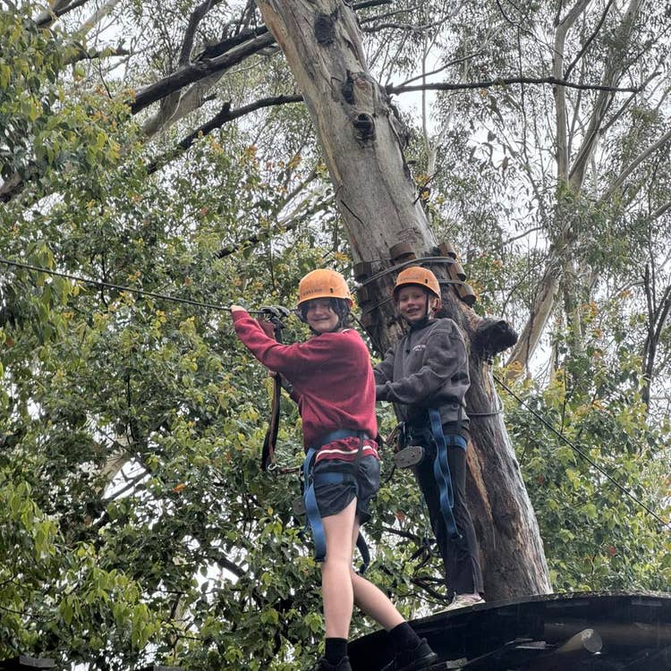 Two Year 6 girls participating in a high ropes course.