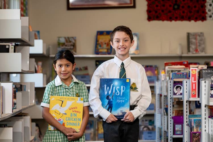 Two students holding books looking at the camera