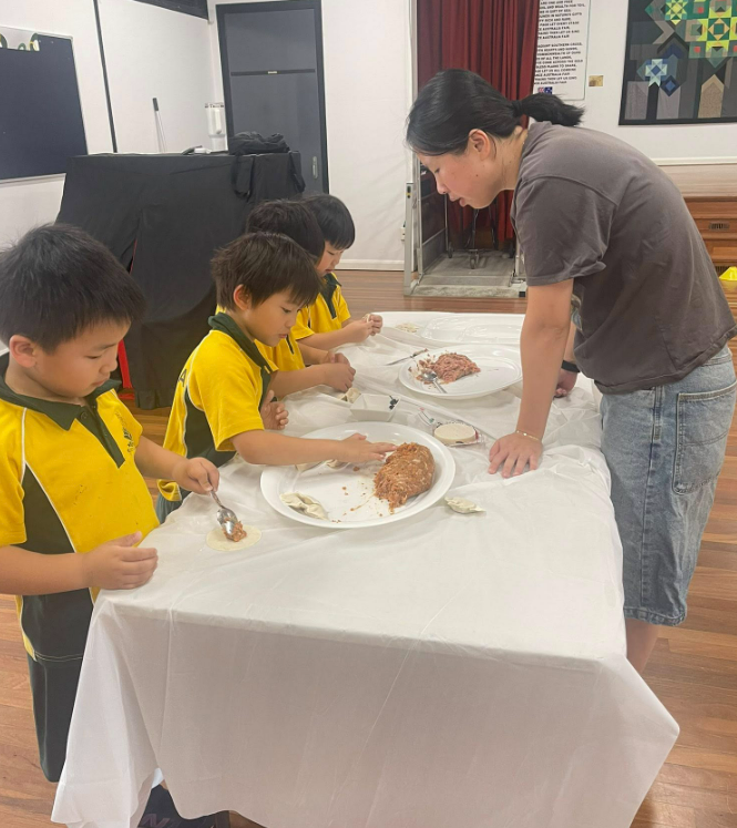 Parent helping students make dumplings