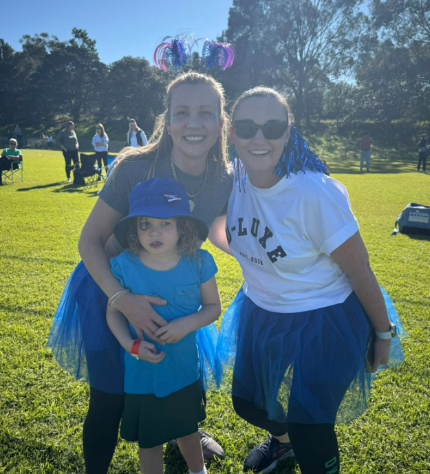 Two parents and a child dressed in blue house colours for the athletics carnival